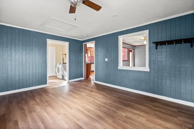 an empty room with wooden floor cabinet and windows