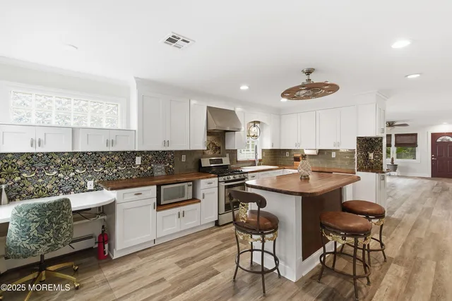 a living room with stainless steel appliances granite countertop a sink and wooden floor