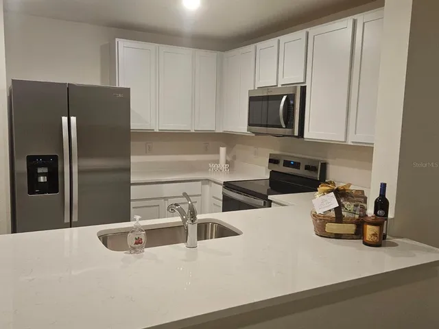 a kitchen with stainless steel appliances granite countertop a refrigerator and a sink