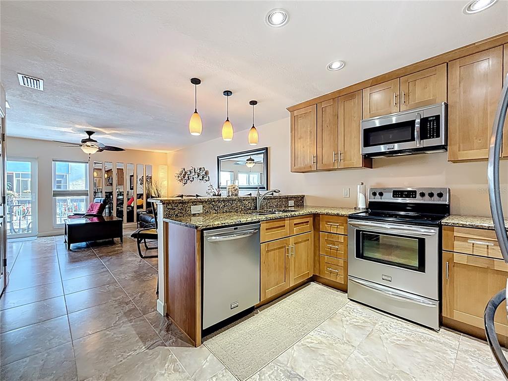230 Medallion Boulevard, Unit G Madeira Beach, FL 33708 - Photo 4 of 44 a kitchen with stainless steel appliances granite countertop a stove sink and cabinets