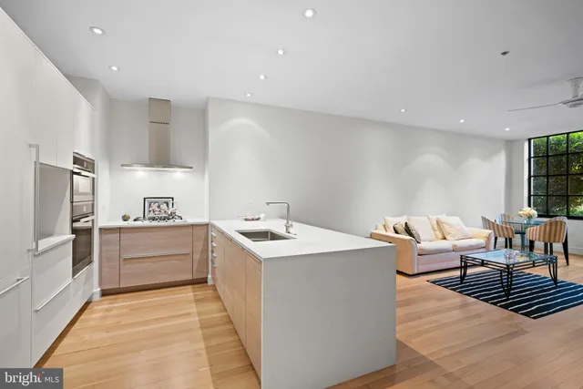 a living room with stainless steel appliances kitchen island granite countertop a sink and wooden cabinets