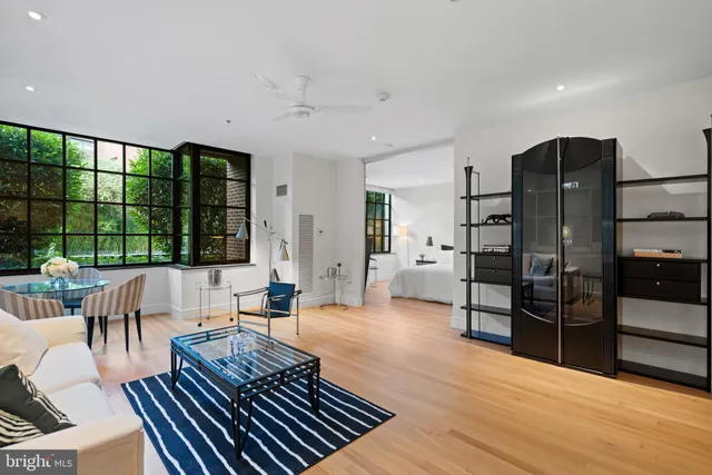 a living room with furniture large window and wooden floor