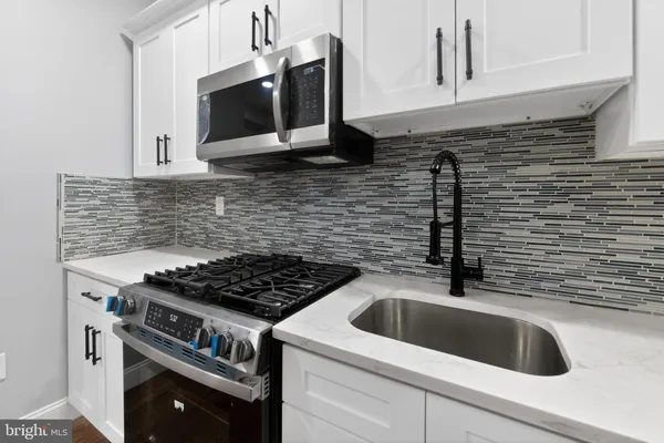 a kitchen with granite countertop a sink stove and microwave