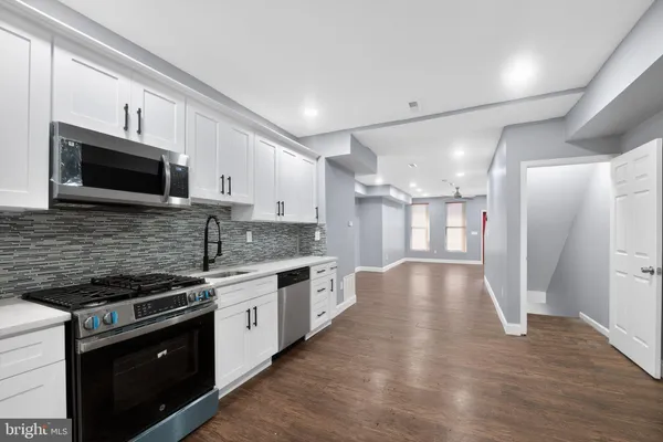 a kitchen with stainless steel appliances granite countertop a stove a sink and a microwave