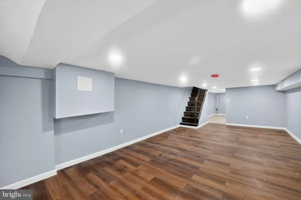 a view of an empty room with wooden floor and stairs