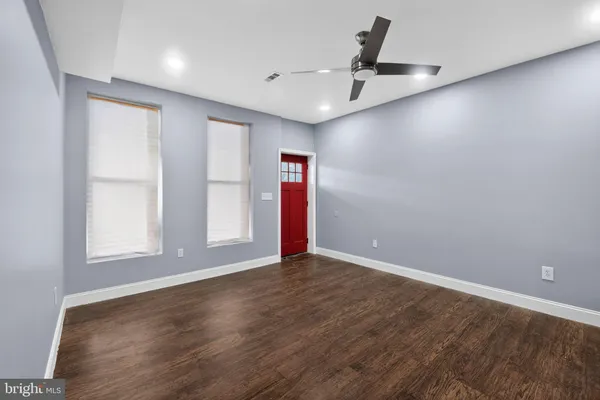 an empty room with wooden floor and windows