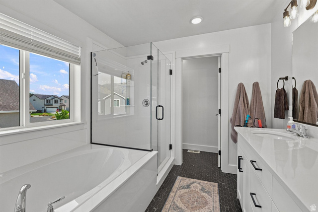 355 West 3085 South Logan, UT 84321 - Photo 27 of 40 Freestanding soaking tub with polished chrome fixtures, glass-enclosed shower with matte black trim, and a white vanity with integrated sink and matte black hardware