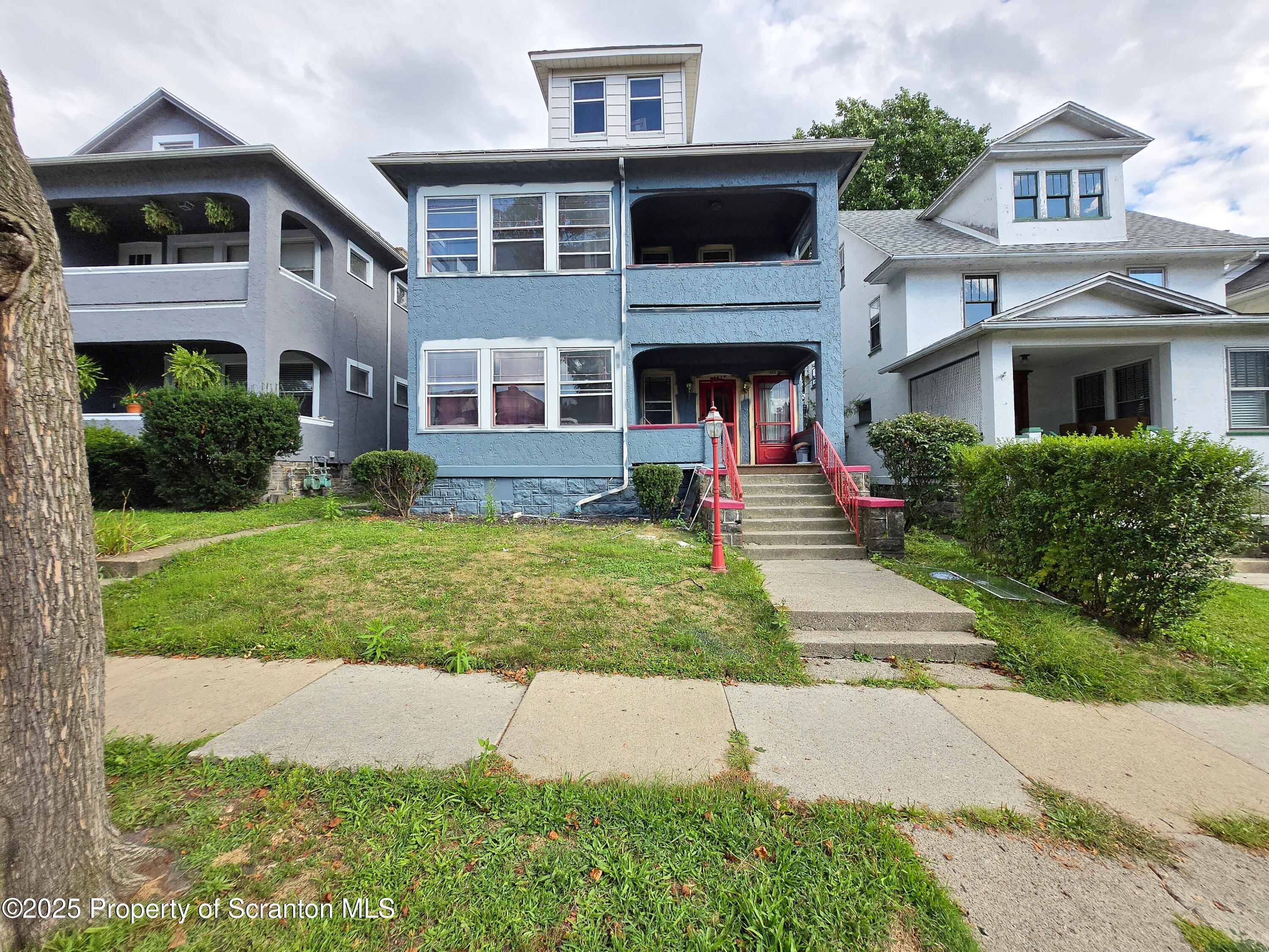 a front view of a house with a yard and potted plants