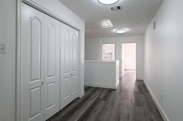 a view of a hallway with wooden floor and a bathroom