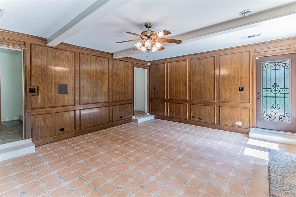 127 Nicklaus Nook Lancaster, TX 75146 - Photo 8 of 37 Unfurnished living room with a ceiling fan, beam ceiling, and wooden walls