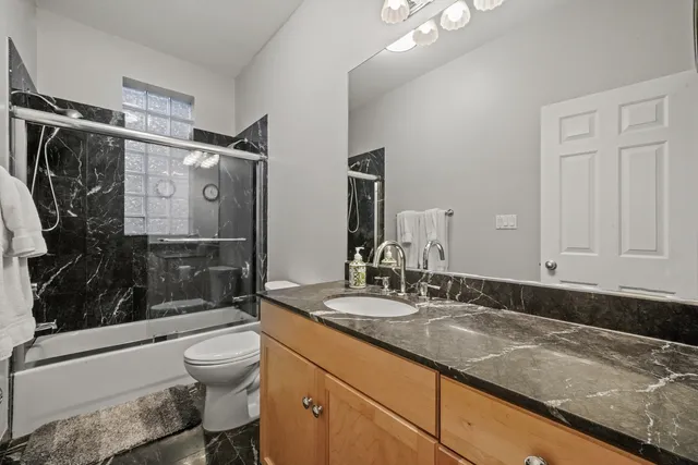 a bathroom with a granite countertop sink toilet and shower
