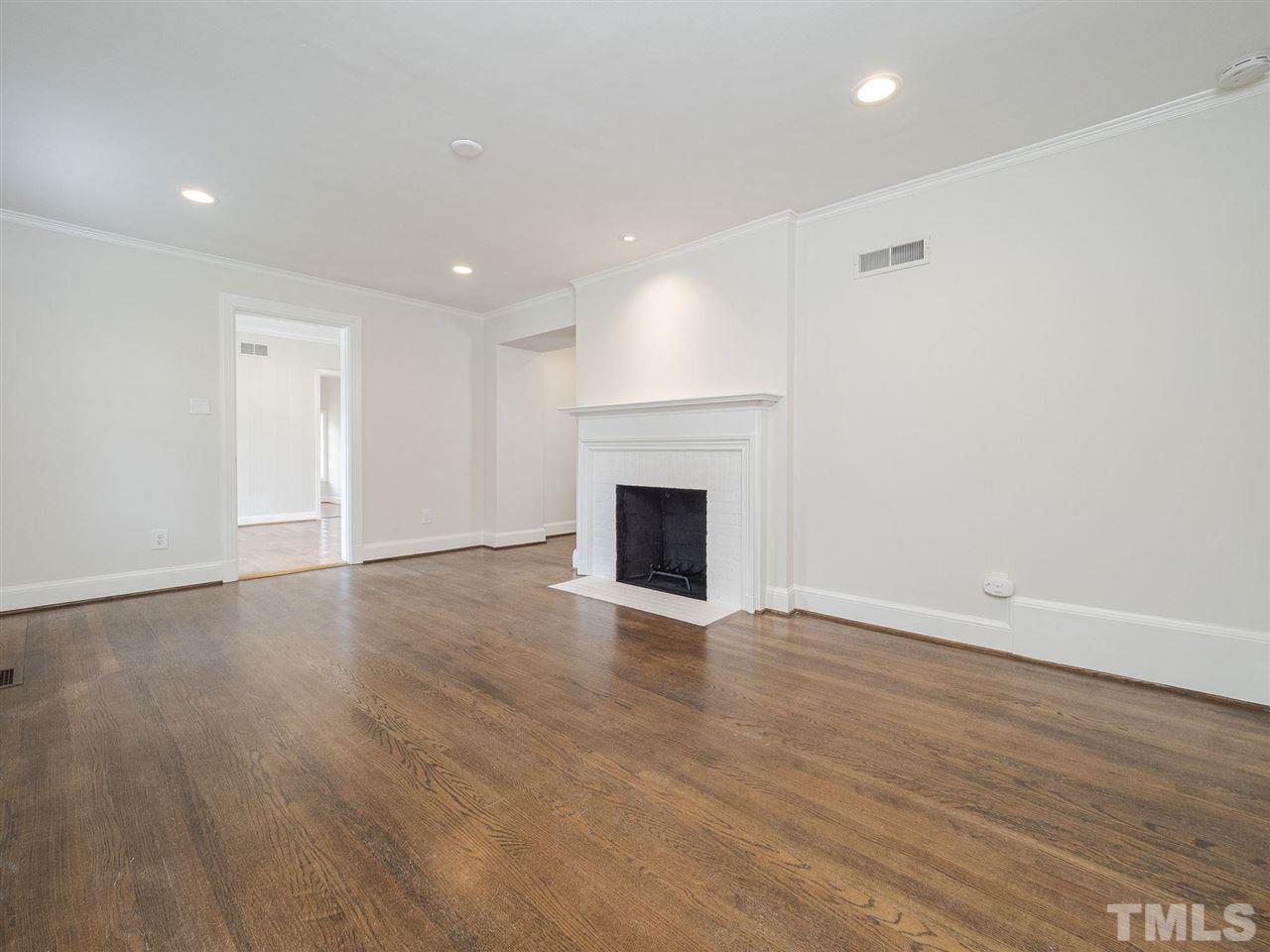 2804 Anderson Drive Raleigh, NC 27608 - Photo 4 of 23 an empty room with wooden floor and fireplace