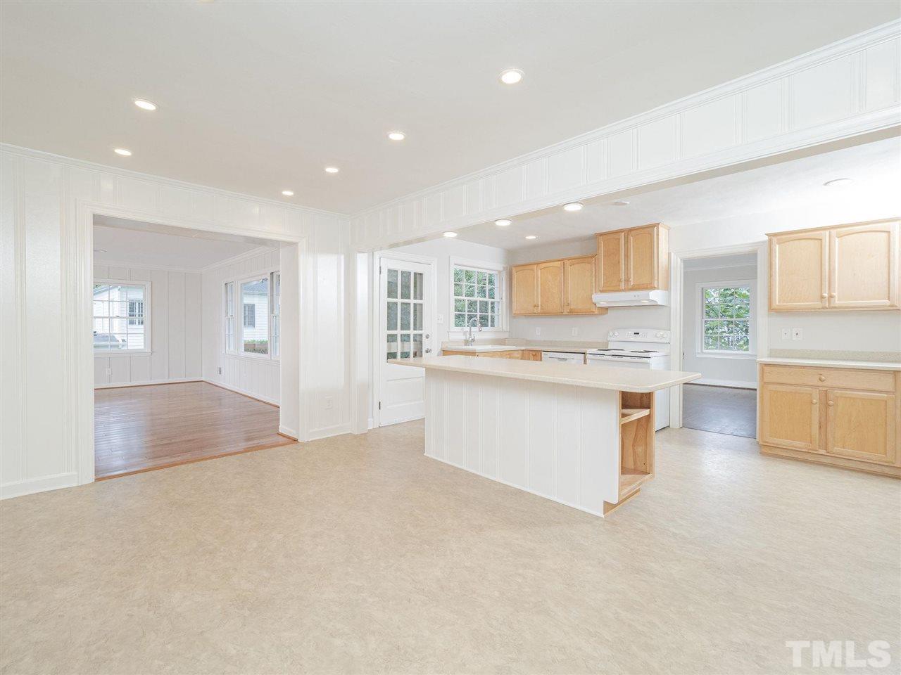 2804 Anderson Drive Raleigh, NC 27608 - Photo 8 of 23 a large white kitchen with a refrigerator a stove a sink a dining table and chair