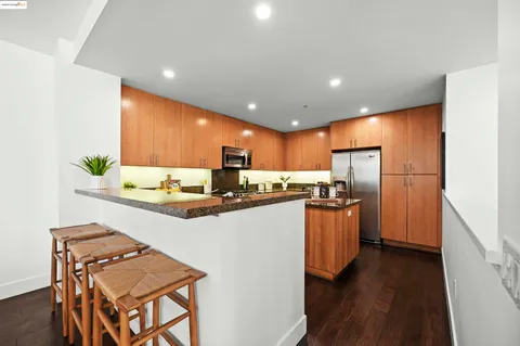 a kitchen with refrigerator and wooden floor