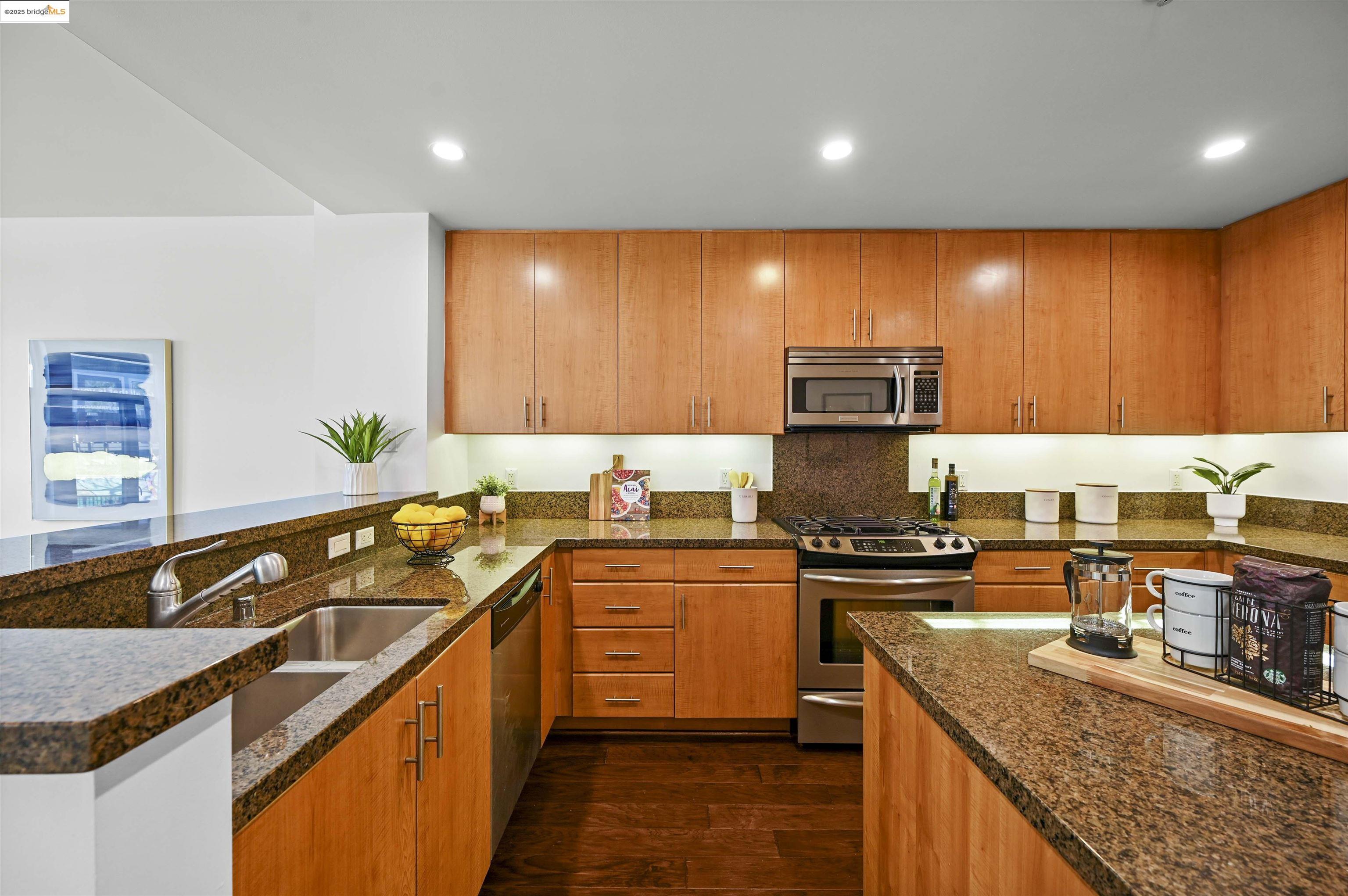 438 West Grand Avenue, Unit 422 Oakland, CA 94612 - Photo 19 of 52 Kitchen featuring dark wood-type flooring, appliances with stainless steel finishes, recessed lighting, a peninsula, and dark stone countertops