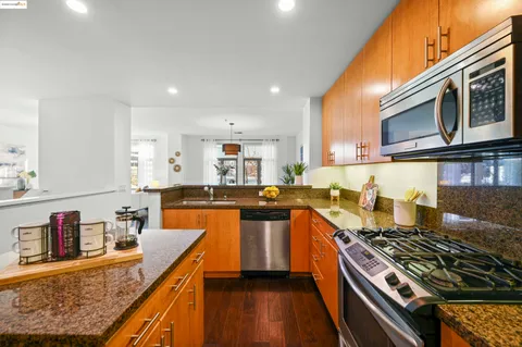 a kitchen with stainless steel appliances granite countertop a stove top oven a sink dishwasher and cabinets with wooden floor