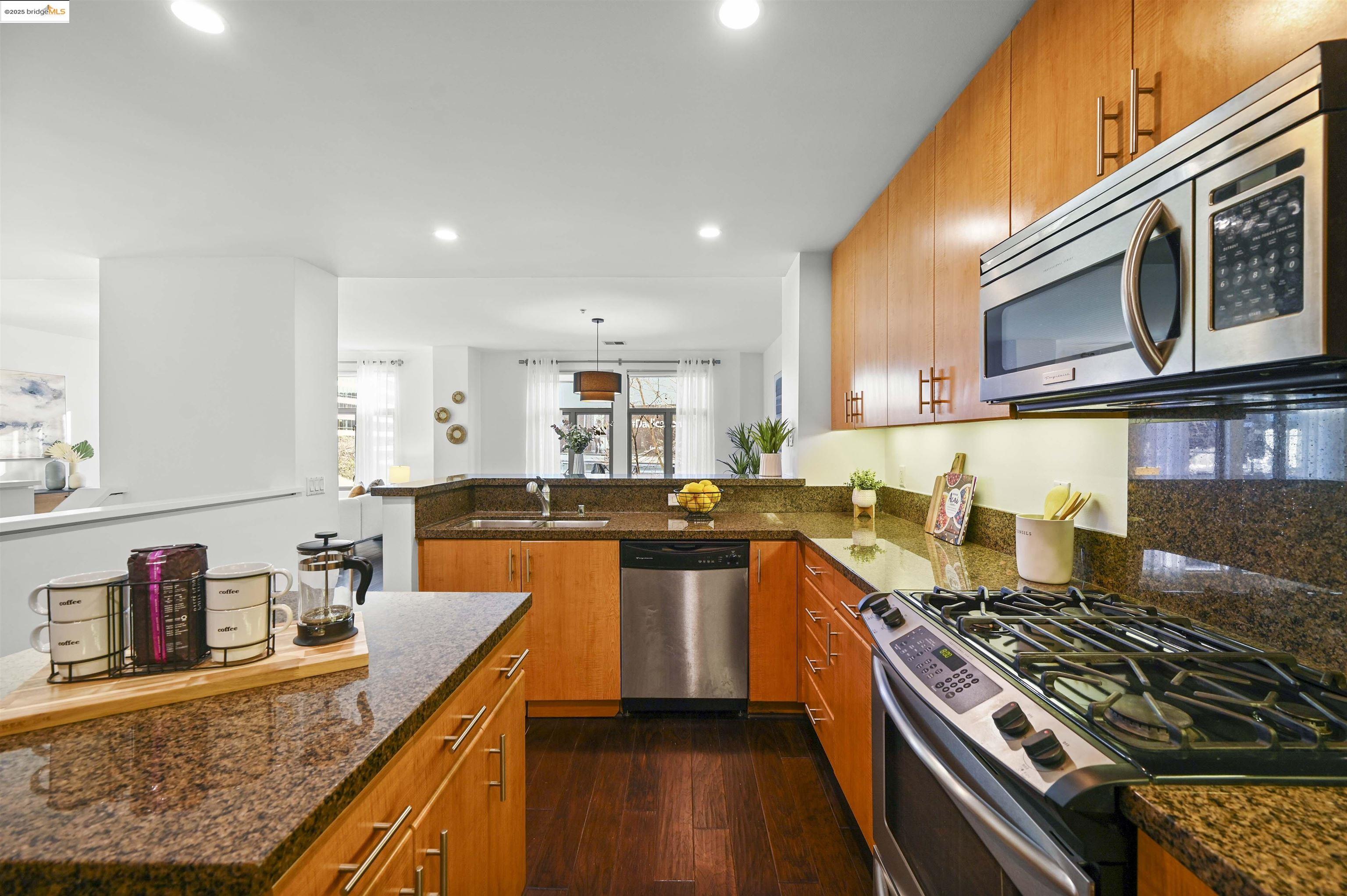 438 West Grand Avenue, Unit 422 Oakland, CA 94612 - Photo 21 of 52 Kitchen featuring appliances with stainless steel finishes, recessed lighting, dark wood-type flooring, a peninsula, and brown cabinets