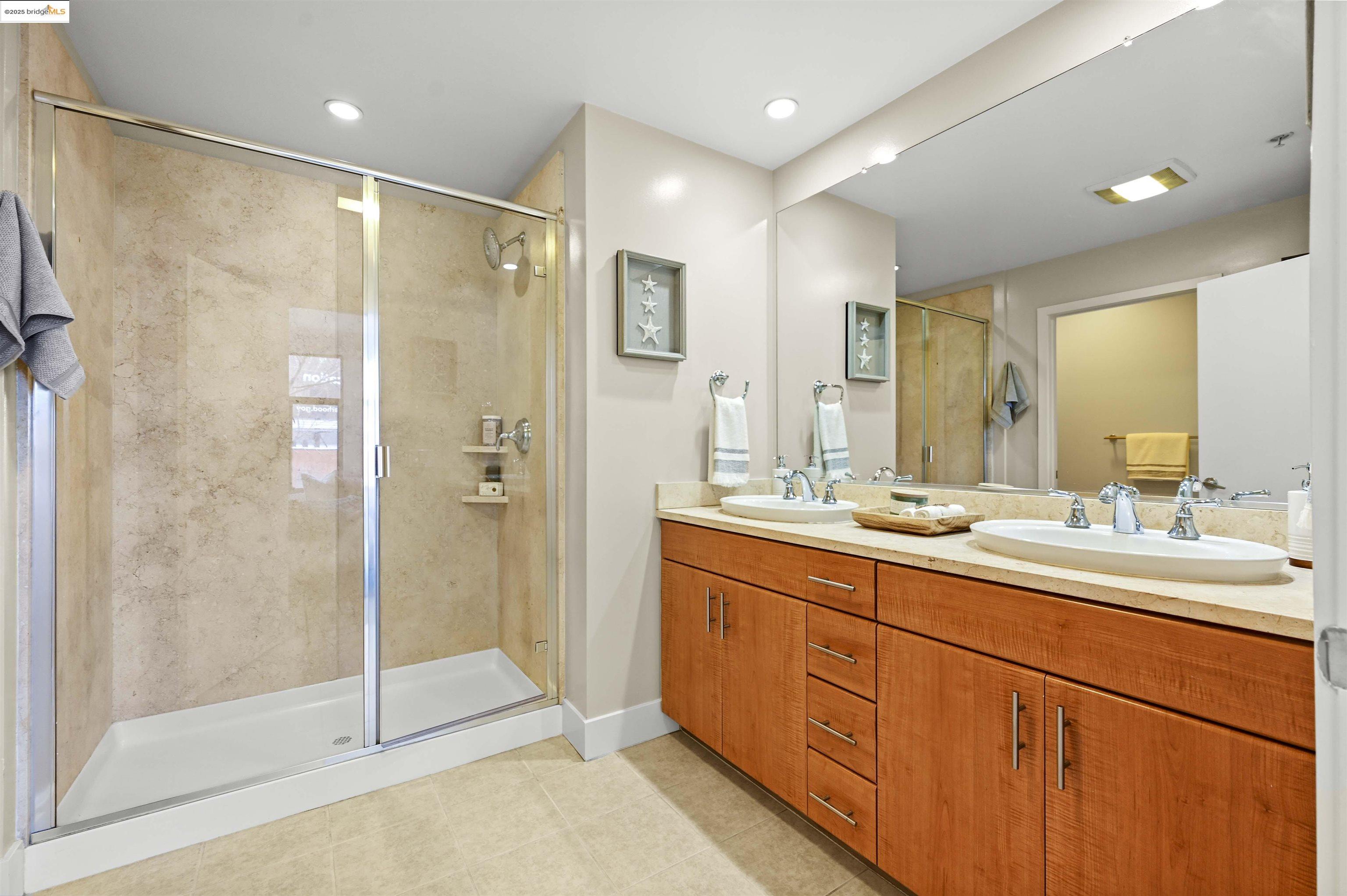 438 West Grand Avenue, Unit 422 Oakland, CA 94612 - Photo 31 of 52 Full bath featuring a shower stall, double vanity, light tile patterned floors, and recessed lighting
