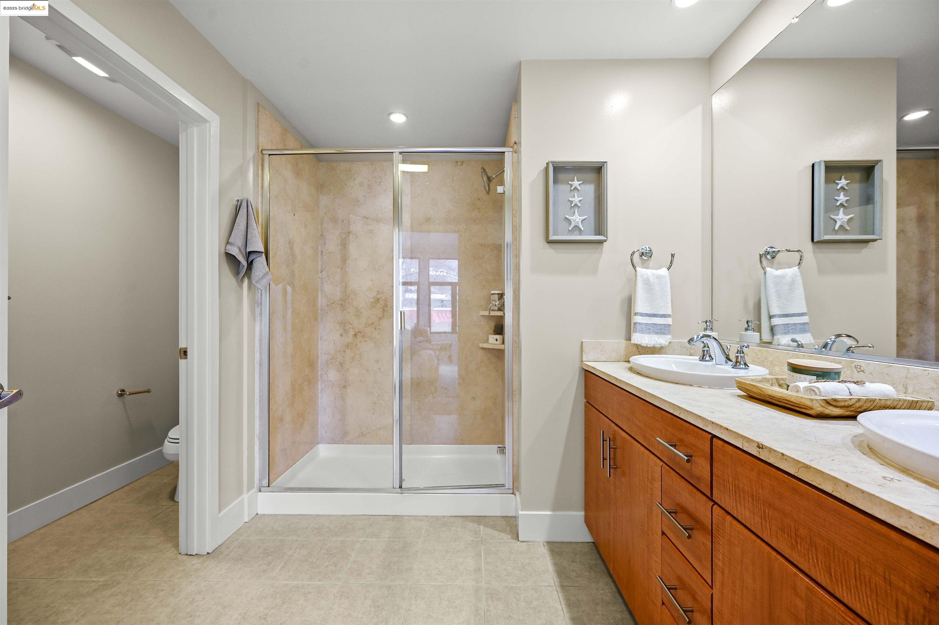 438 West Grand Avenue, Unit 422 Oakland, CA 94612 - Photo 32 of 52 Full bathroom featuring double vanity, a stall shower, recessed lighting, and light tile patterned floors