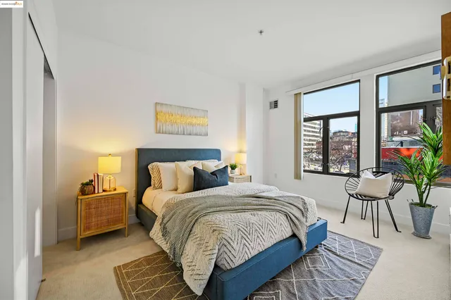a spacious bedroom with a bed a bookshelf and a potted plant