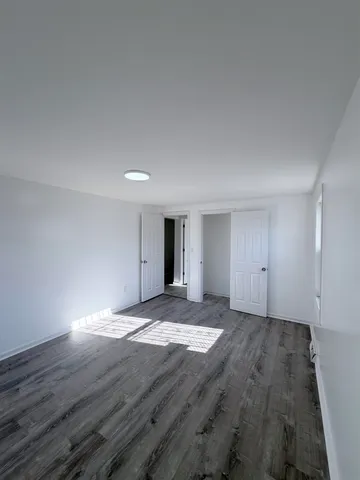 a view of an empty room with wooden floor and windows