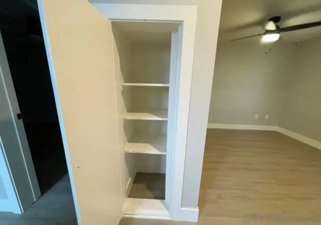 en empty room with wooden floor and fan