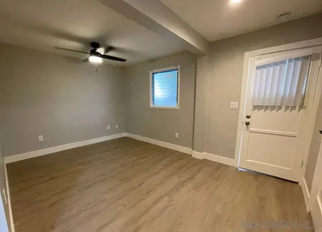 an empty room with wooden floor closet ceiling fan and windows