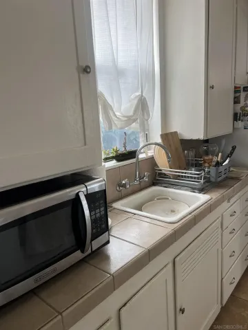 a kitchen with granite countertop white cabinets sink and stove