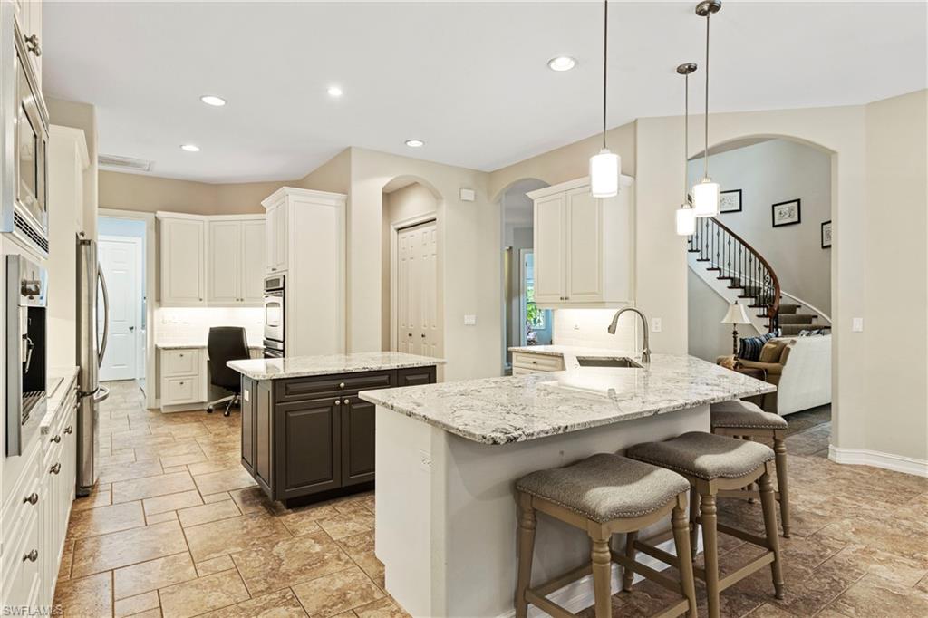 2116 Harlans Run Naples, FL 34105 - Photo 15 of 35 Kitchen featuring arched walkways, recessed lighting, stone tile floors, a breakfast bar area, and a peninsula