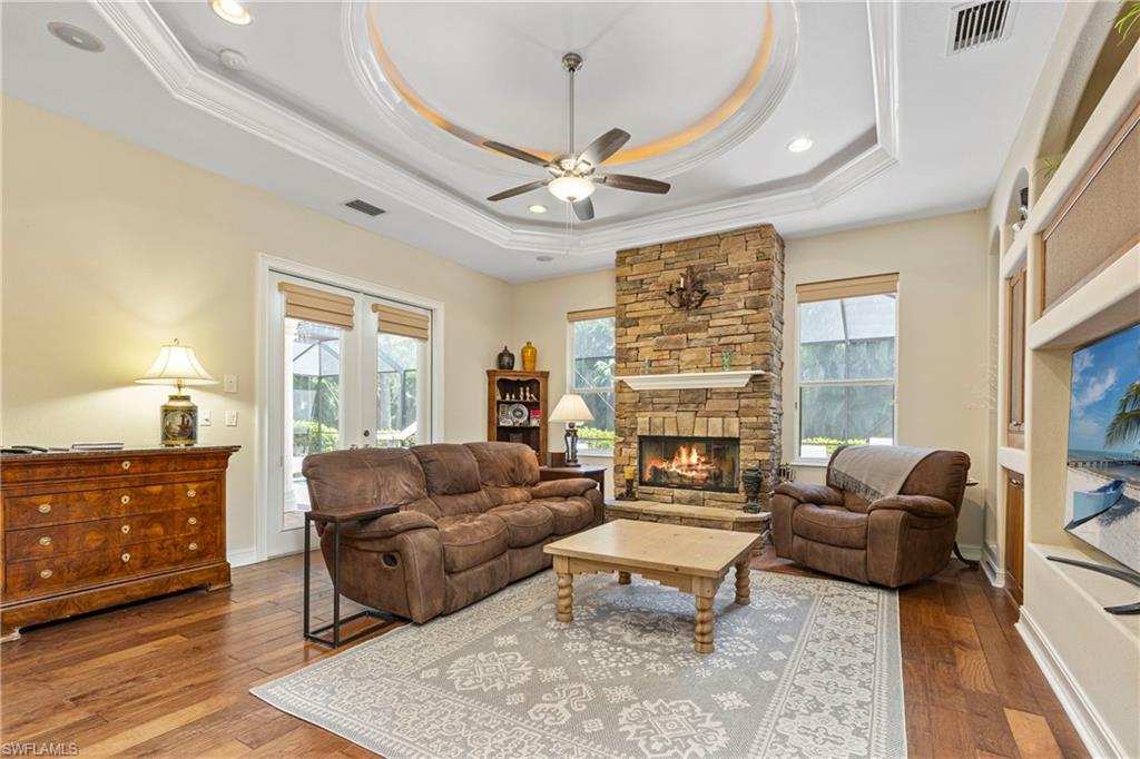 2116 Harlans Run Naples, FL 34105 - Photo 17 of 35 Living room featuring healthy amount of natural light, crown molding, ceiling fan, hardwood / wood-style flooring, and a stone fireplace