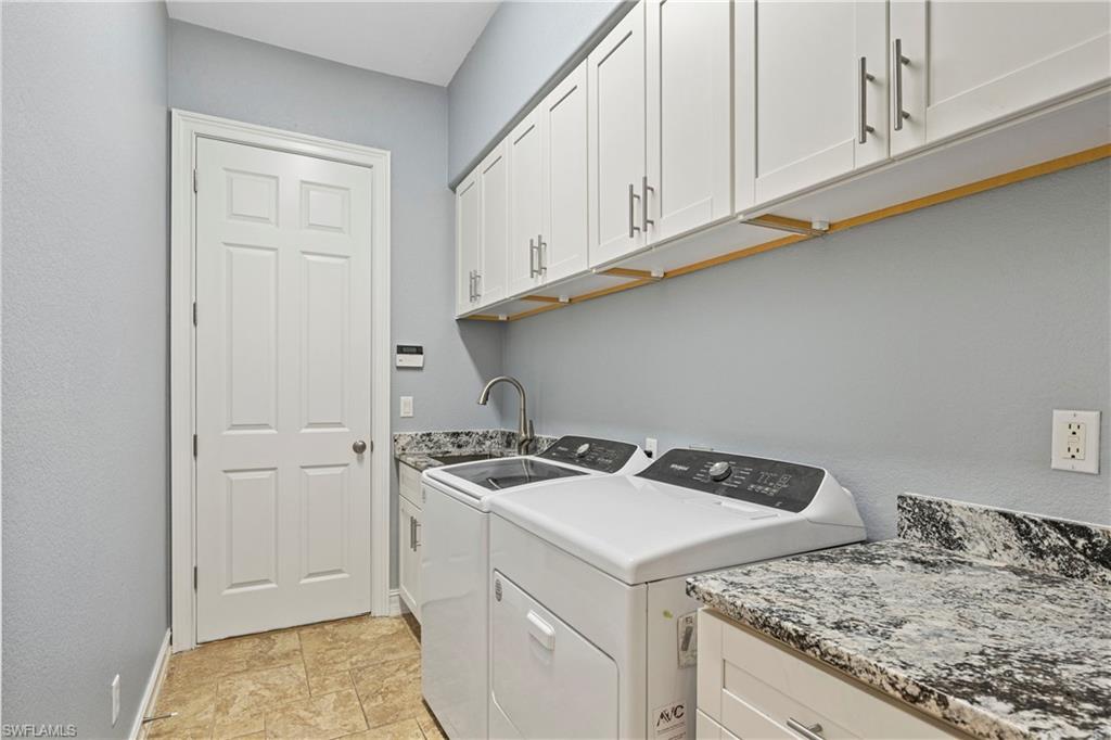 2116 Harlans Run Naples, FL 34105 - Photo 22 of 35 Washroom featuring washing machine and clothes dryer, cabinet space, and a textured wall