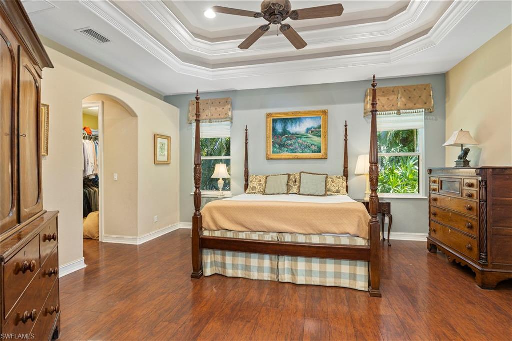 2116 Harlans Run Naples, FL 34105 - Photo 23 of 35 Bedroom with crown molding, arched walkways, wood finished floors, a walk in closet, and a raised ceiling