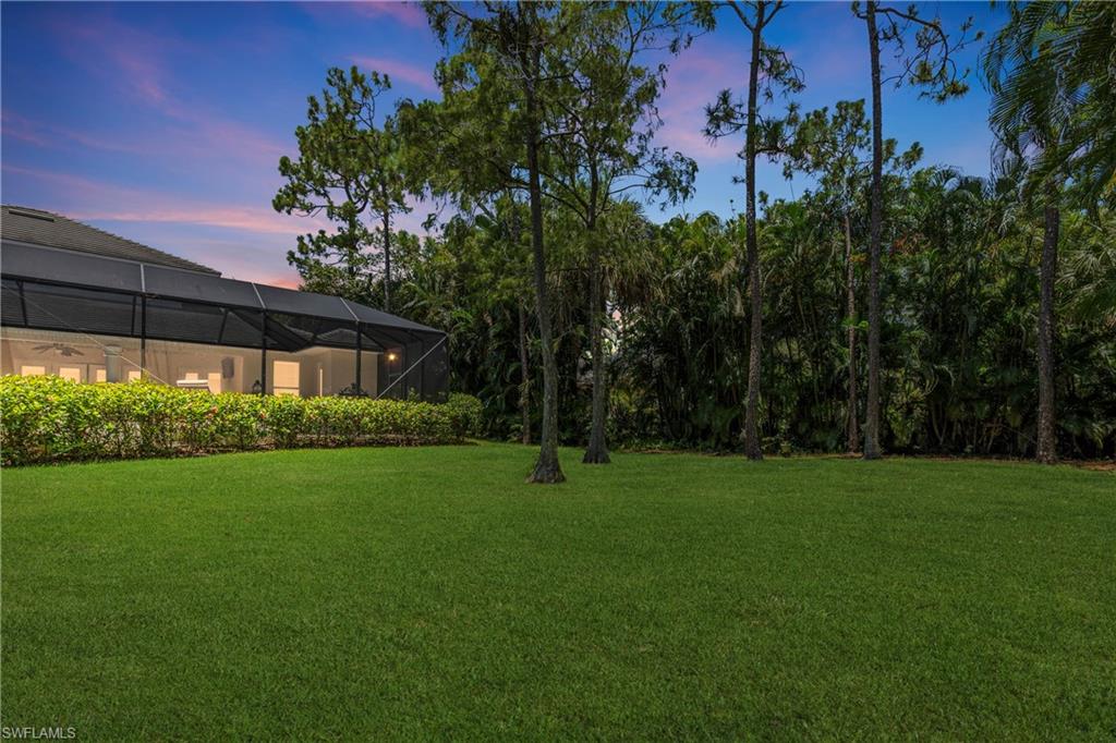 2116 Harlans Run Naples, FL 34105 - Photo 30 of 35 Yard at dusk featuring a lawn and glass enclosure