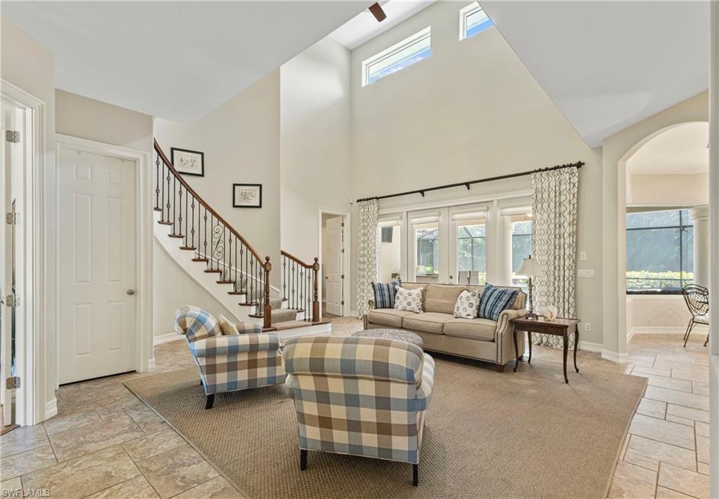 2116 Harlans Run Naples, FL 34105 - Photo 5 of 35 Living room featuring arched walkways, stone tile floors, and stairway