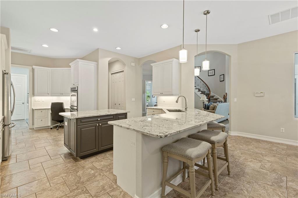 2116 Harlans Run Naples, FL 34105 - Photo 9 of 35 Kitchen featuring arched walkways, stone finish flooring, a peninsula, recessed lighting, and a breakfast bar