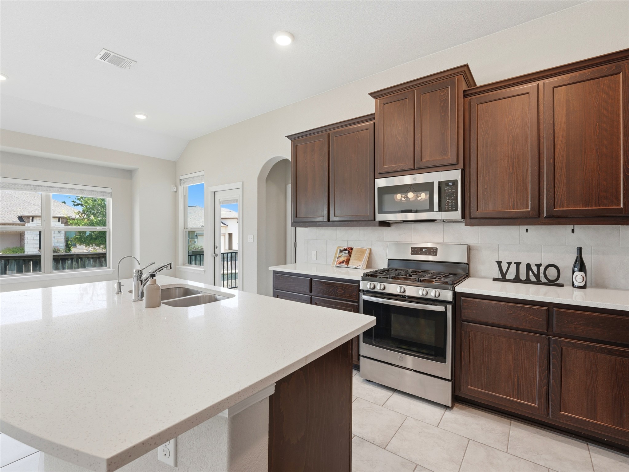2132 Ringstaff Road Leander, TX 78641 - Photo 16 of 39 A pristine kitchen features dark wood cabinetry, stainless steel appliances, and a spacious island with a double sink.