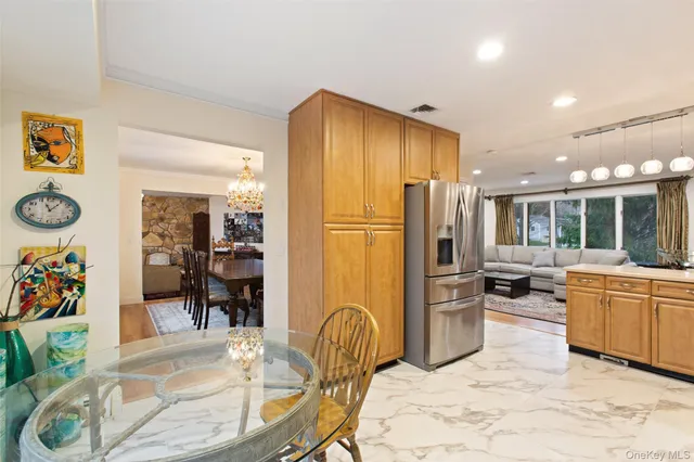 a kitchen with stainless steel appliances granite countertop a refrigerator a stove a dining table and chairs with wooden floor