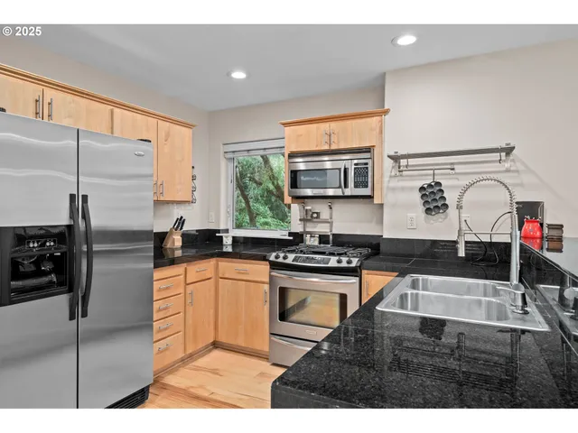 a kitchen with stainless steel appliances granite countertop a sink stove and refrigerator