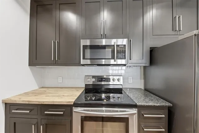 a kitchen with granite countertop stainless steel appliances a stove microwave and sink