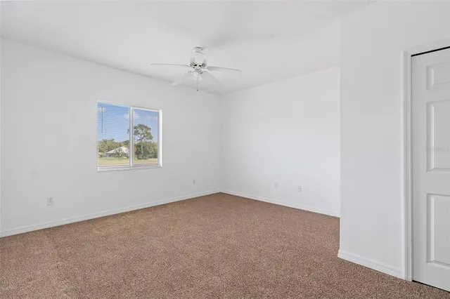 an empty room with a window and a ceiling fan