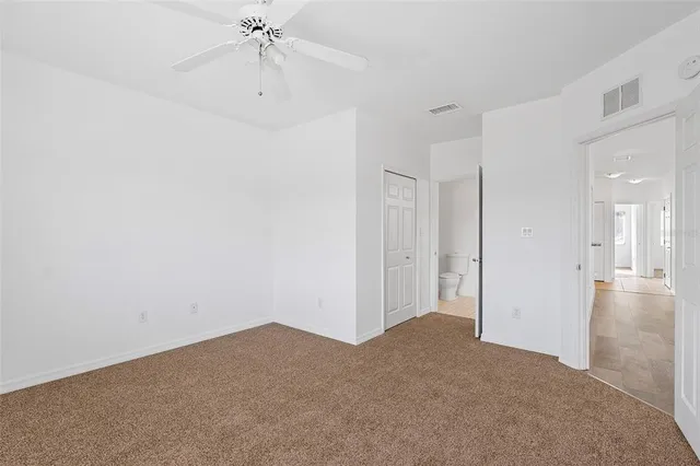 a view of a room with a ceiling fan and closet area