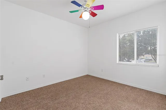 an empty room with a window and a fan