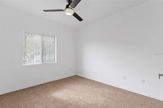 an empty room with a window and a fan