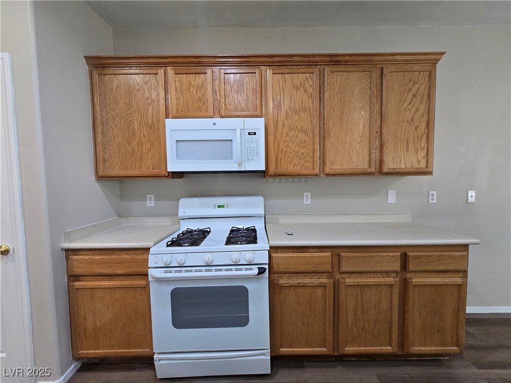 9560 Parker Springs Court Las Vegas, NV 89166 - Photo 13 of 37 Kitchen with white appliances, light countertops, and brown cabinets