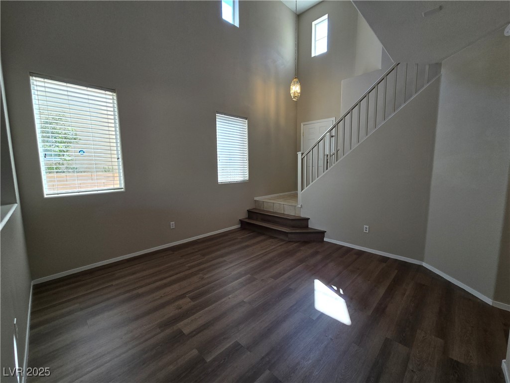9560 Parker Springs Court Las Vegas, NV 89166 - Photo 8 of 37 Unfurnished living room with dark wood-type flooring, stairway, and a high ceiling