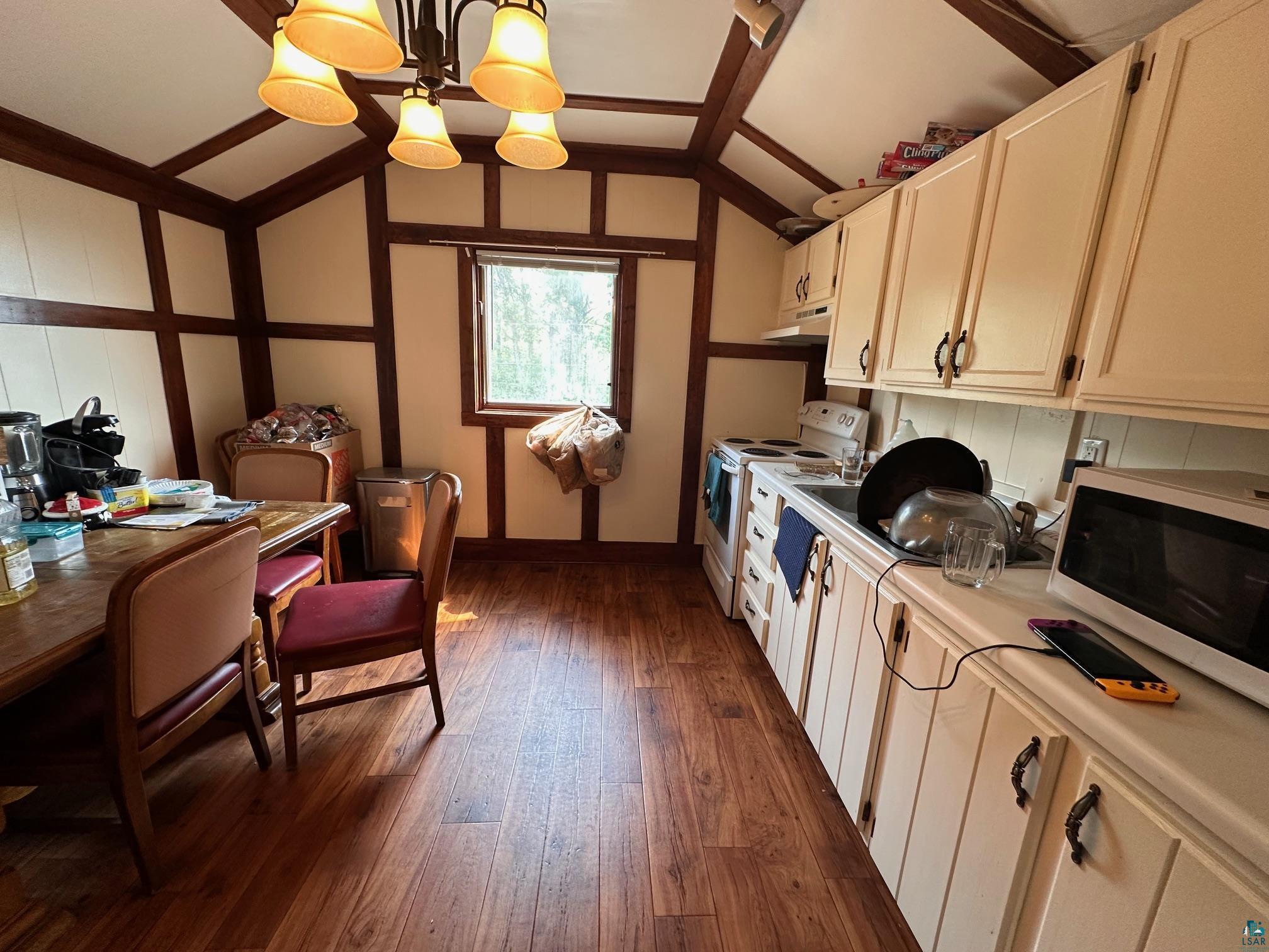1601 4th Avenue International Falls, MN 56649 - Photo 34 of 50 Kitchen with white appliances, dark wood-style floors, light countertops, under cabinet range hood, and lofted ceiling
