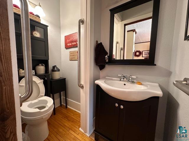 1601 4th Avenue International Falls, MN 56649 - Photo 4 of 50 Half bath featuring wood finished floors, toilet, vanity, and baseboards