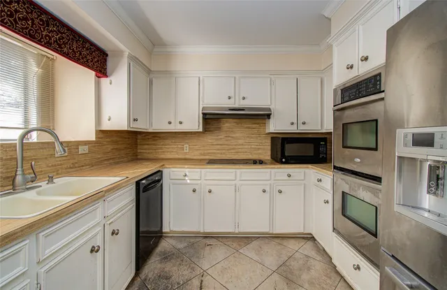 a kitchen with granite countertop white cabinets stainless steel appliances a sink and a window