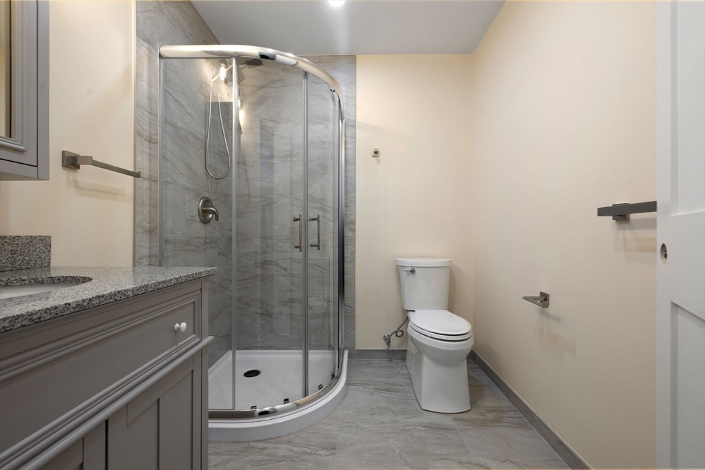 123 Nottinghill Road, Unit 2 Boston, MA 02135 - Photo 22 of 30 a bathroom with a granite countertop toilet a sink and shower