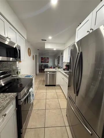 a kitchen with granite countertop a refrigerator and a stove top oven